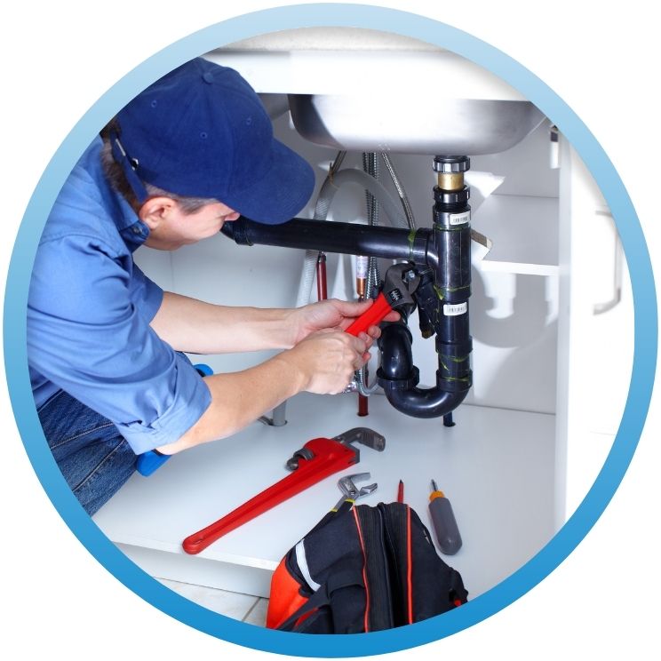 Plumber using a wrench on a black P-trap assembly.