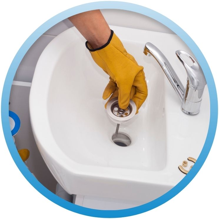 Gloved hand installing a chrome strainer in a sink.