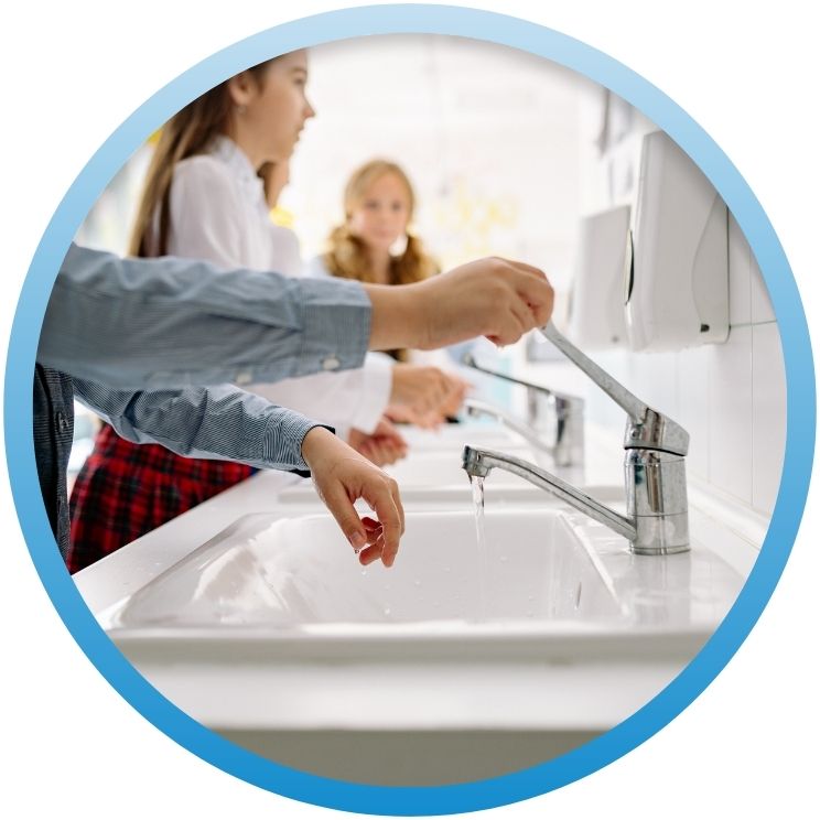 Children washing hands at a row of school sinks.