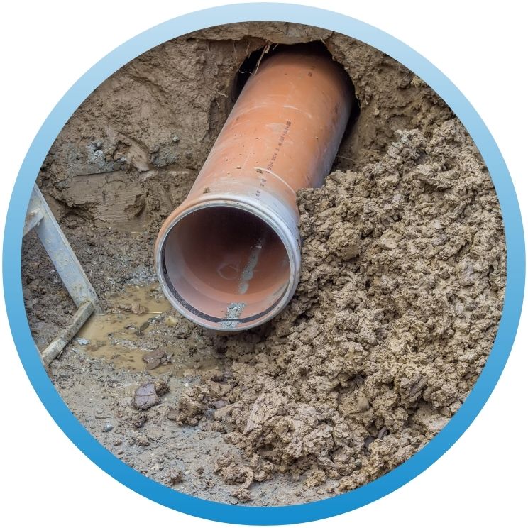 Large orange underground drainage pipe emerging from an earthen tunnel.