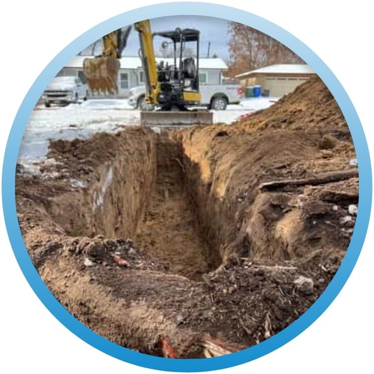 Deep outdoor trench excavated by a mini-excavator for new main lines.