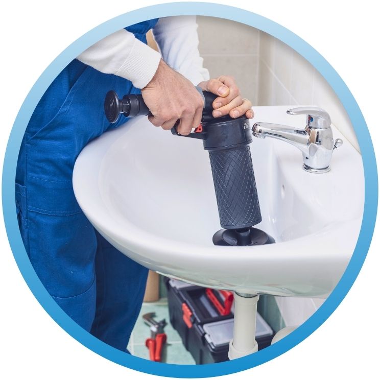 Plumber using a hand-held kinetic water ram to clear a sink.