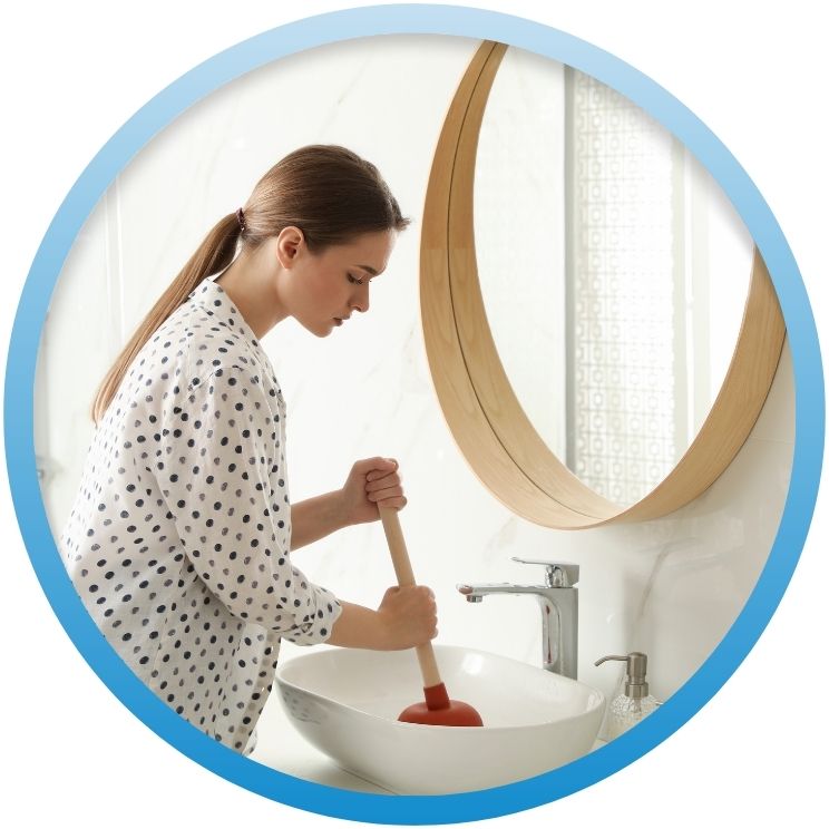 Woman using a standard plunger on a white vessel sink.