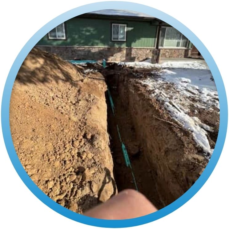 Long outdoor trench showing a new green drainage pipe installation.