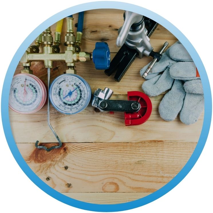 HVAC tools including manifold gauges and pipe cutters on wood.