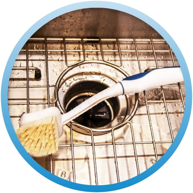 Scrubbing brush cleaning a stainless steel sink drain
