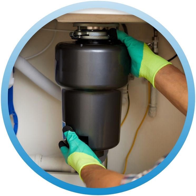 Gloved hands installing a new garbage disposal unit.