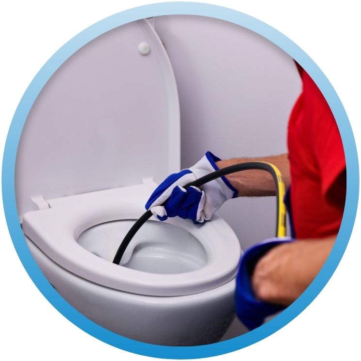 Gloved hand feeding a high-pressure jetting hose into a toilet