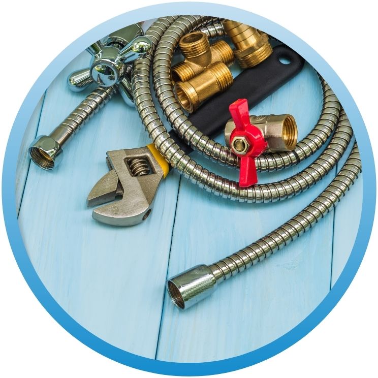 Flat lay of flexible metal hoses, brass fittings, and tools.