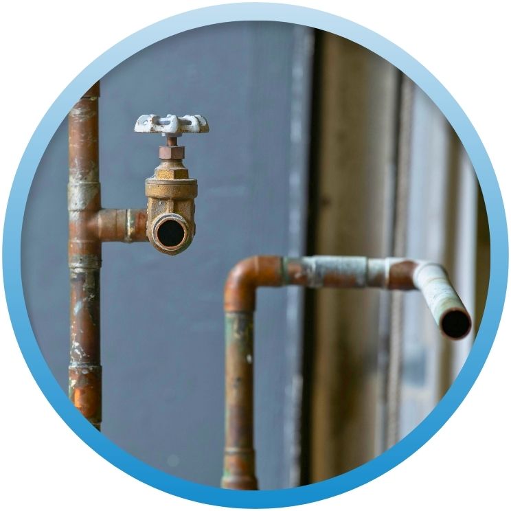 Aged copper piping with a manual shut-off valve.
