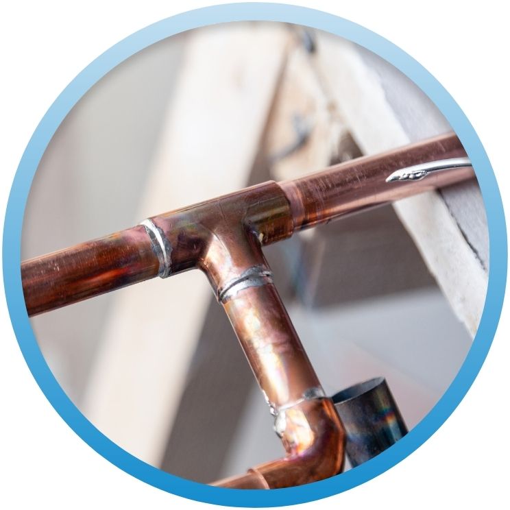 Close-up of a newly soldered copper pipe T-junction.