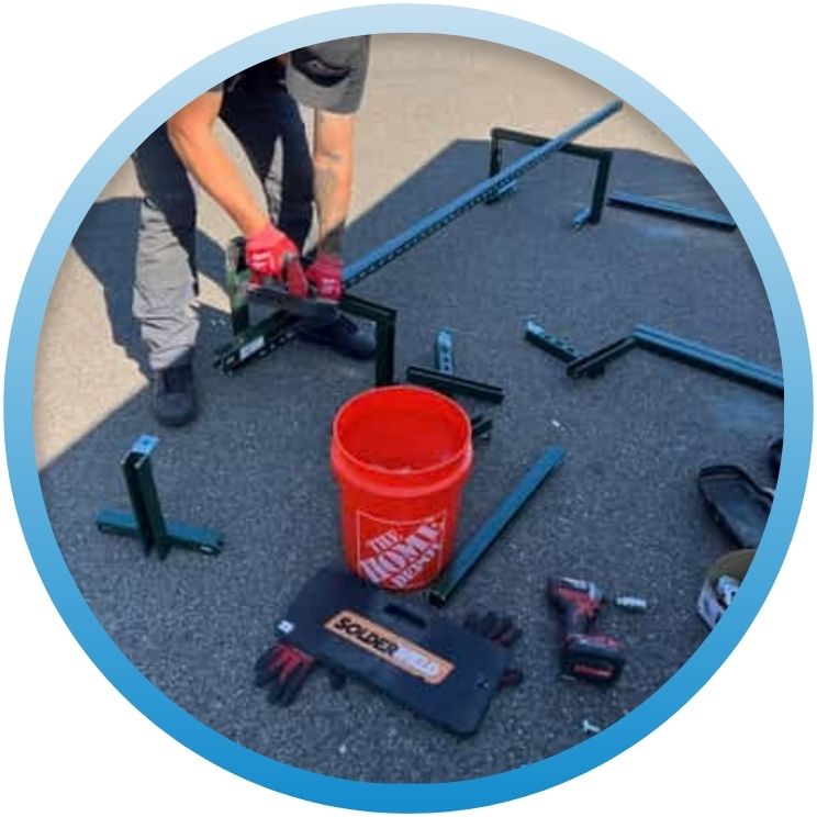 technician assembling metal support brackets outdoors near a bucket.