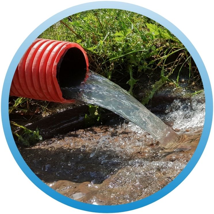 High-volume water discharge flowing from a red corrugated drainage pipe.