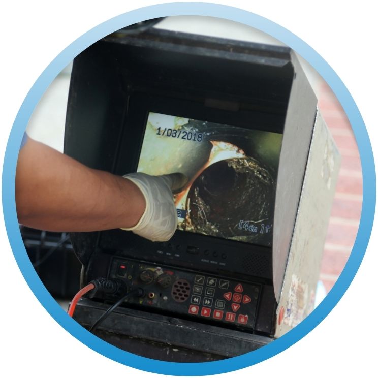 Technician pointing to a pipe blockage on a video inspection monitor.