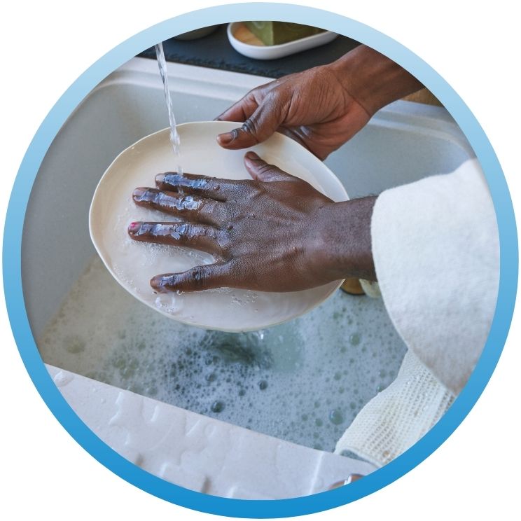 Close-up of hands washing a plate under running water.