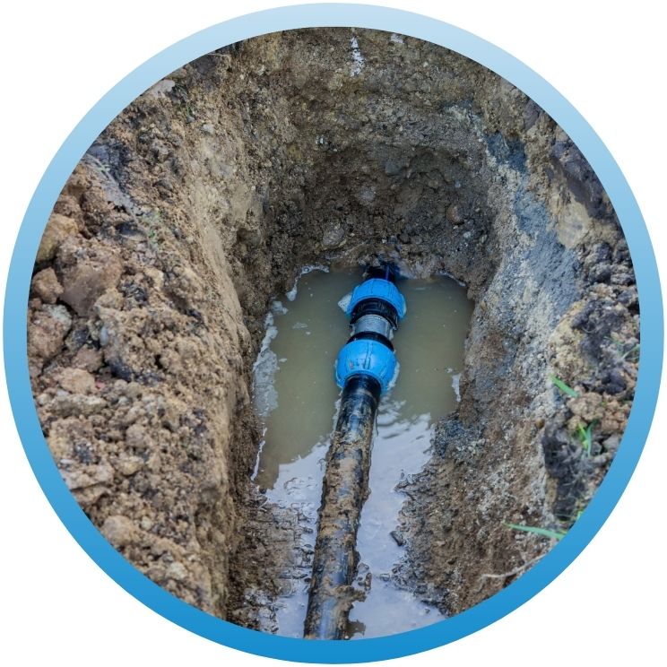 Main water line repair in a deep trench with blue couplings.