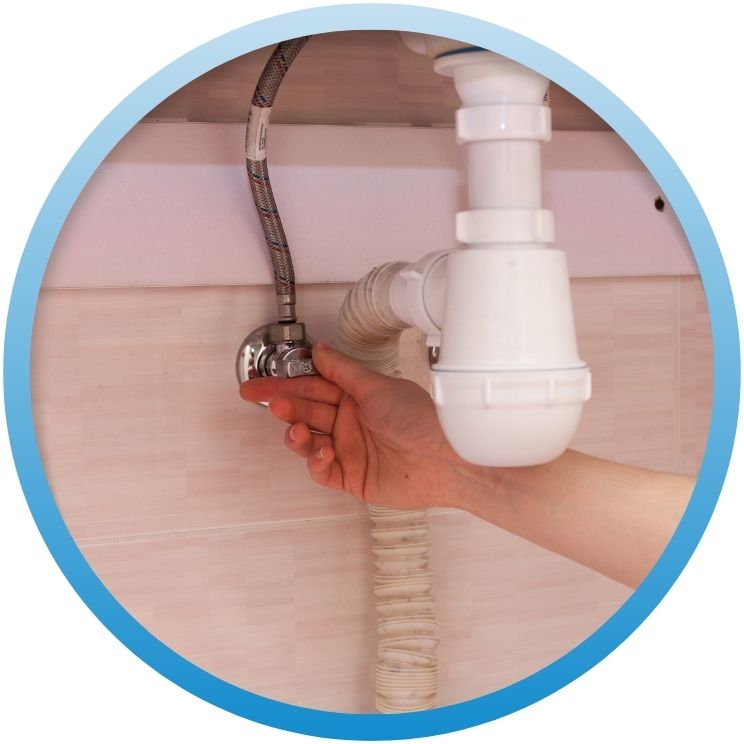 Hand turning a white plastic under-sink shut-off valve.