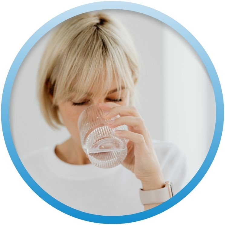 Woman drinking a clear glass of filtered water.