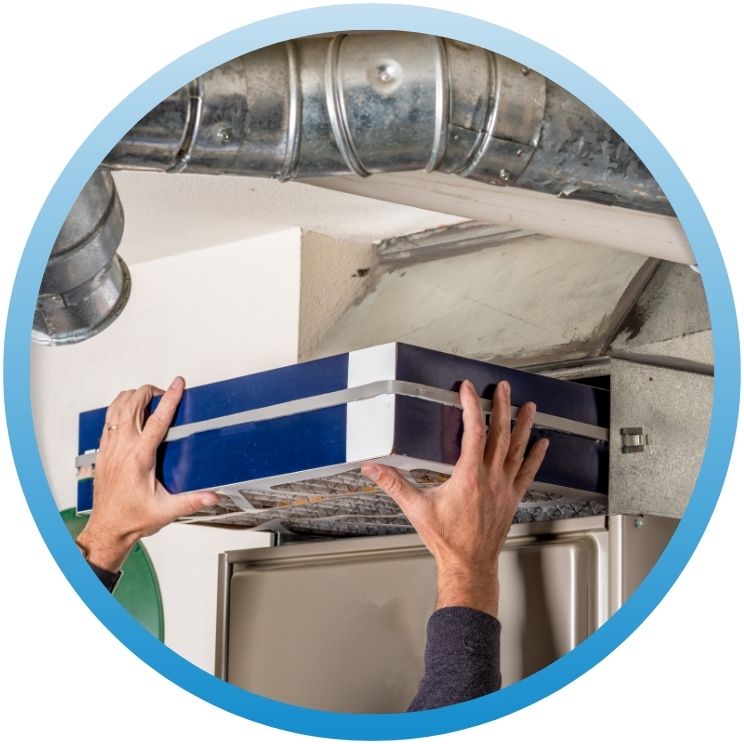 Technician installing a new thick air filter into HVAC.