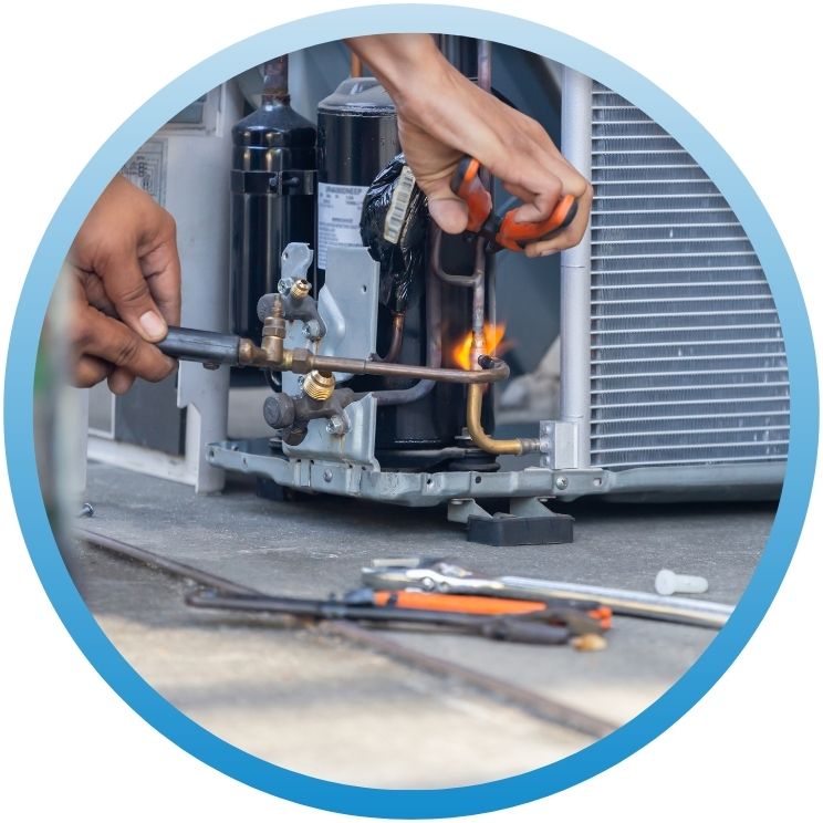 Close-up of technician brazing copper pipes on AC unit.