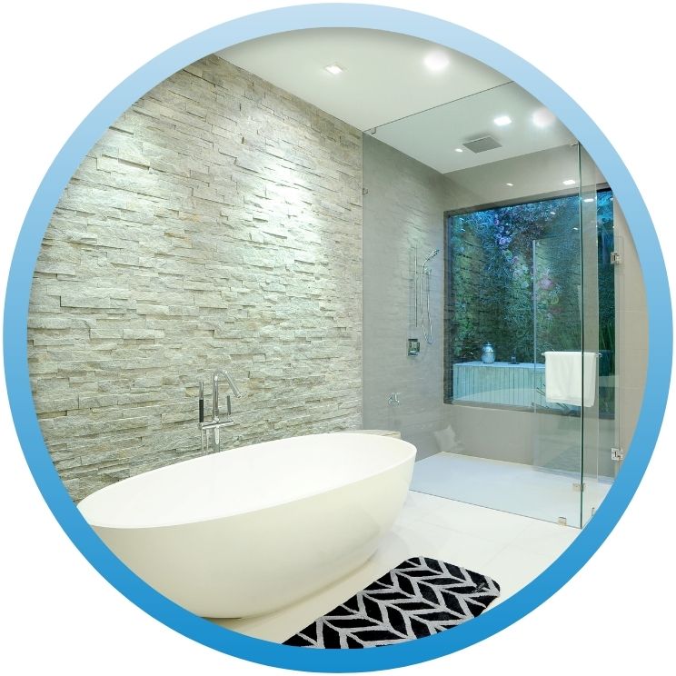 Luxury bathroom featuring stone wall and oval soaking tub.