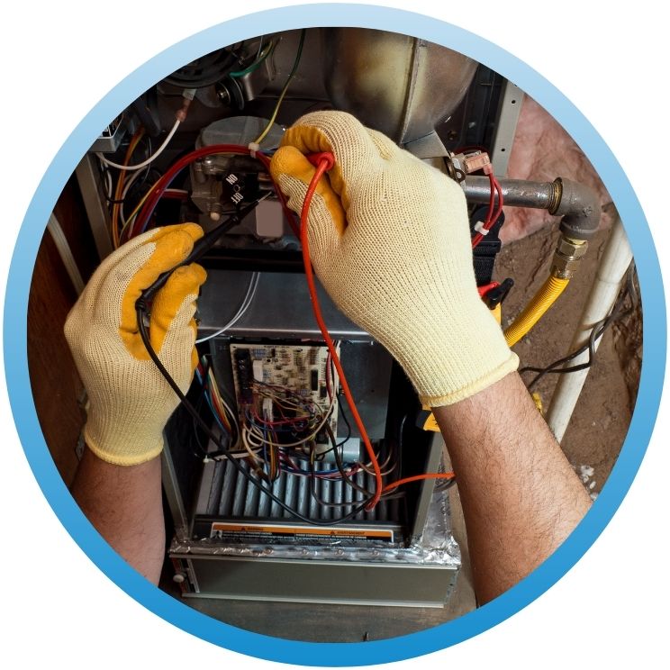 Hands using a multimeter on furnace electrical wiring.