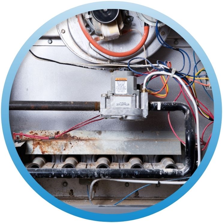 Close-up of gas valves and burners inside furnace.