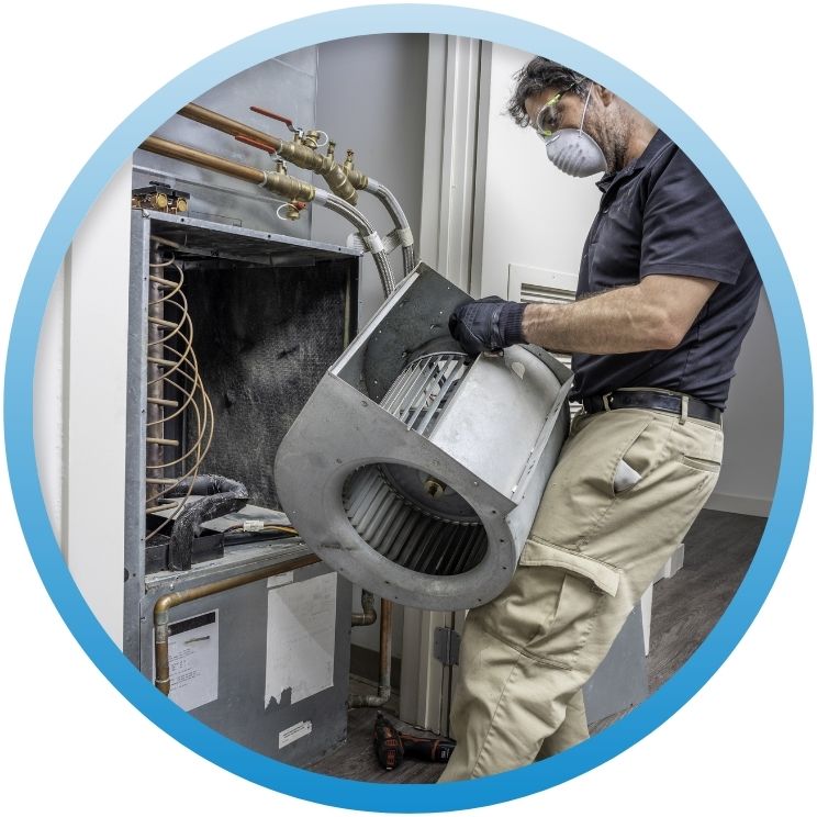 Technician removing a metal blower fan from a furnace.