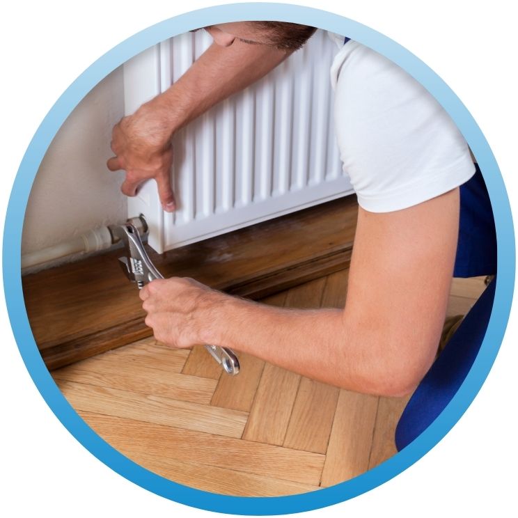 Technician using a wrench to tighten a radiator valve.