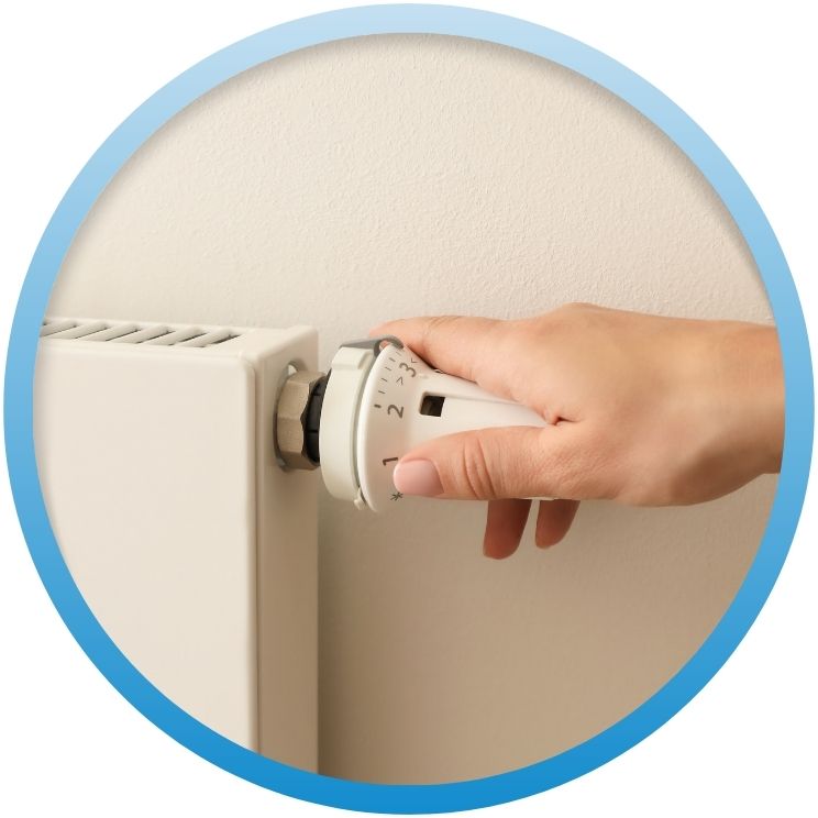 Hand adjusting the white thermostatic valve on a radiator.